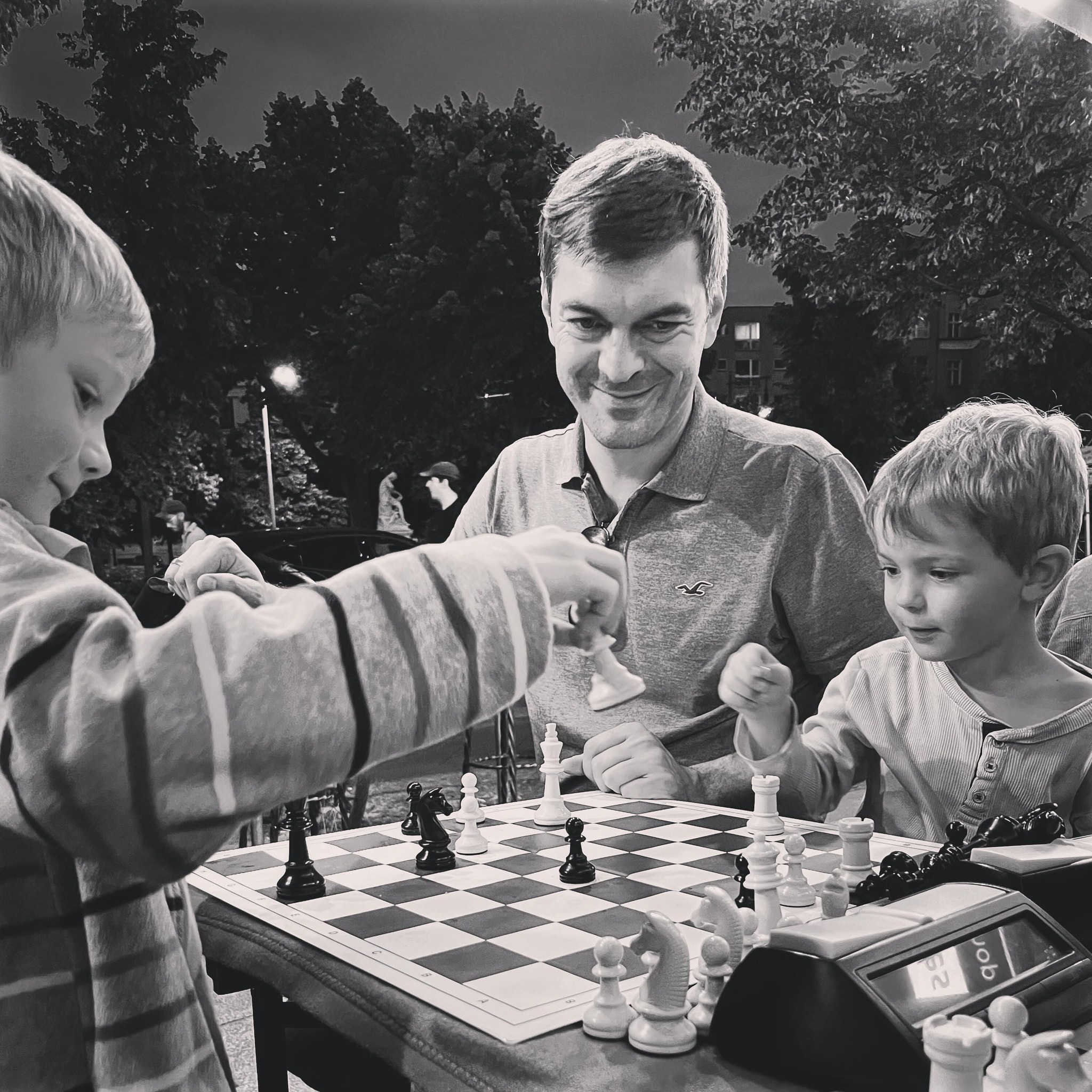 Young people standing around the counter playing chess over the board