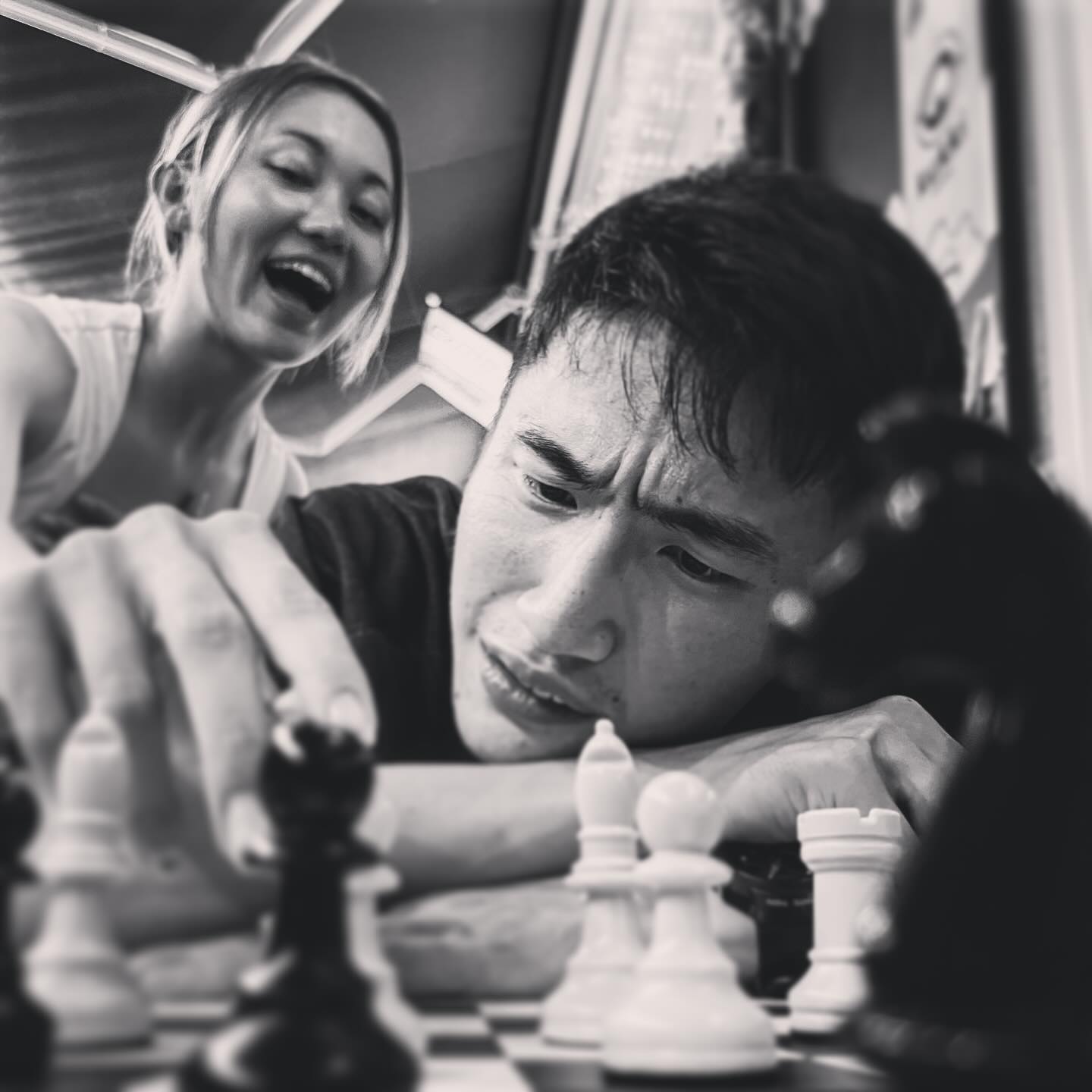 Young people standing around the counter playing chess over the board