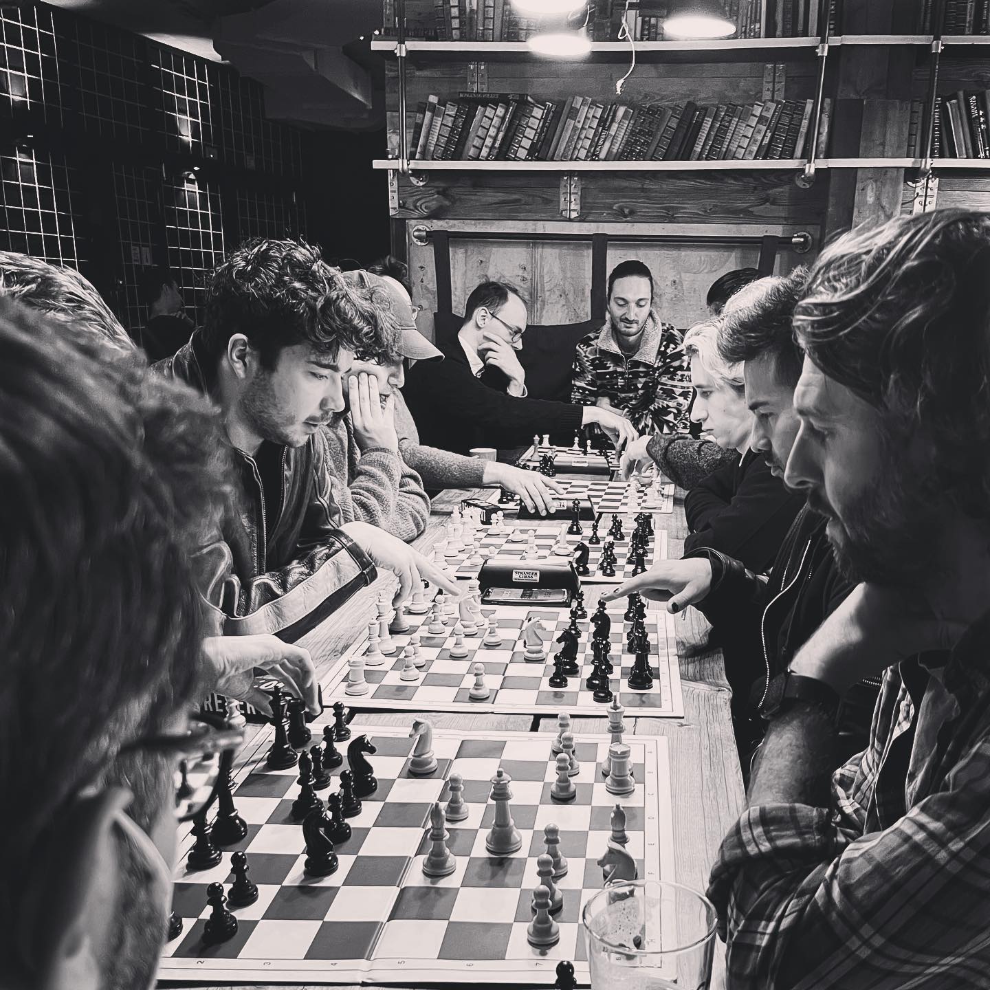 A group of people playing chess on a long table