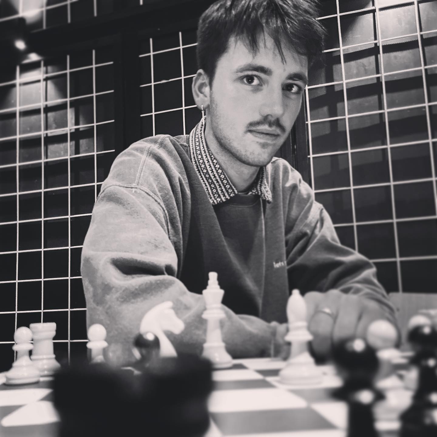 A young man infront of a chessboard looking at the camera