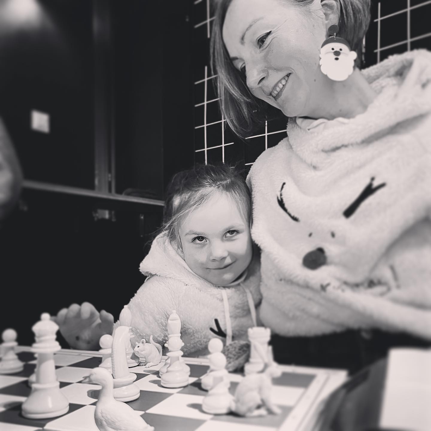 A mother and her young daughter sitting at the chessboard